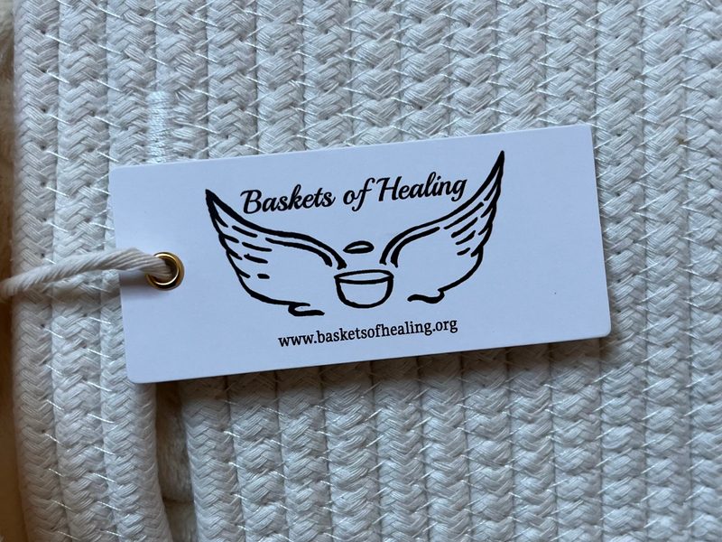 Close-up of a Baskets of Healing tag on a cream rope basket